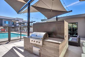 A modern outdoor kitchen with a grill and an umbrella.